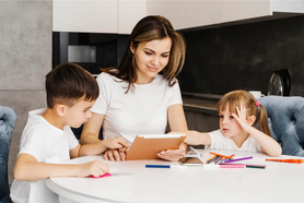 Una mamá enseñándoles de forma cariñosa a sus pequeños actividades lúdicas para la lecto- escritura de formas divertidas para llamar su atención