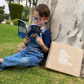 Niño manteniendo el hábito de lectura durante las vacaciones de verano, creando un espacio de lectura invitante en casa, teniendo en cuenta la importancia de la lectura para el desarrollo emocional infantil