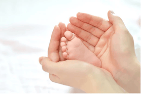 Las manos de una mamá agarrando unos piecitos, reflejando el cuidado del recién nacido, después de haber buscado consejos para padres primerizos, como la preparación emocional para la llegada del bebé